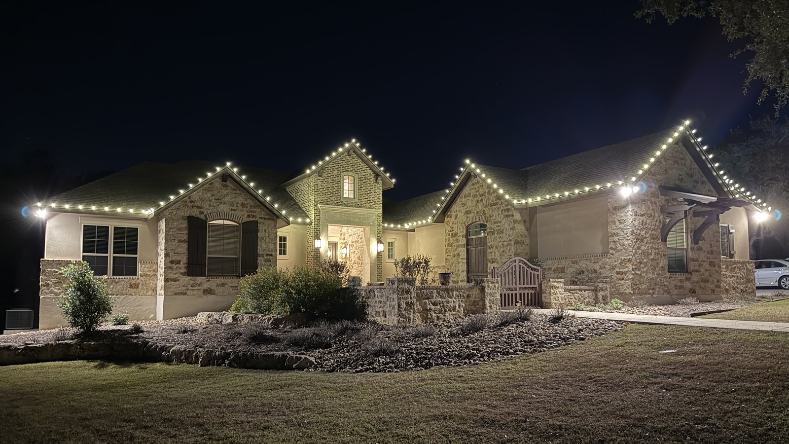 The same home at night with C9 Christmas lights lit along the roofline